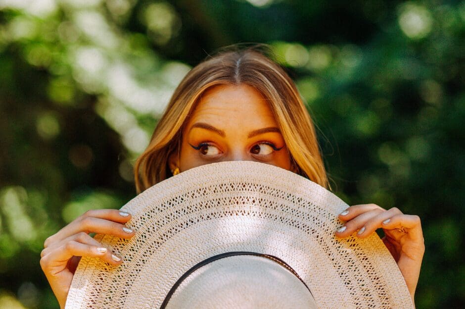 woman looking sideways and hiding her lower face with a big hat