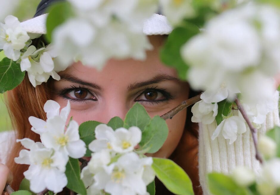 woman with eyes visible hiding the melasma on her face behind white flowers